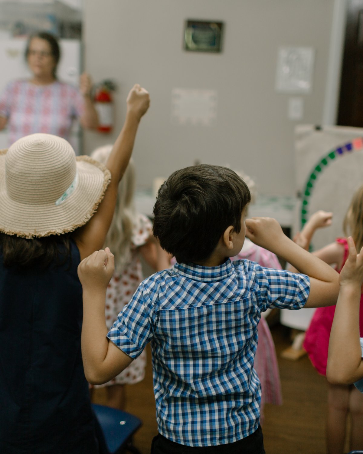 Children with arms raised during a children's chapel song.
