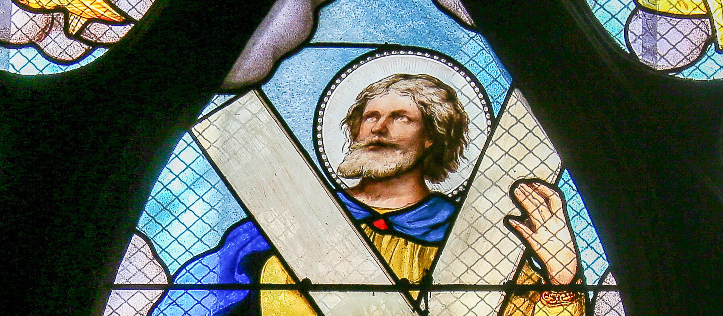 A stained-glass window depicting St. Andrew the Apostle holding the saltire cross.